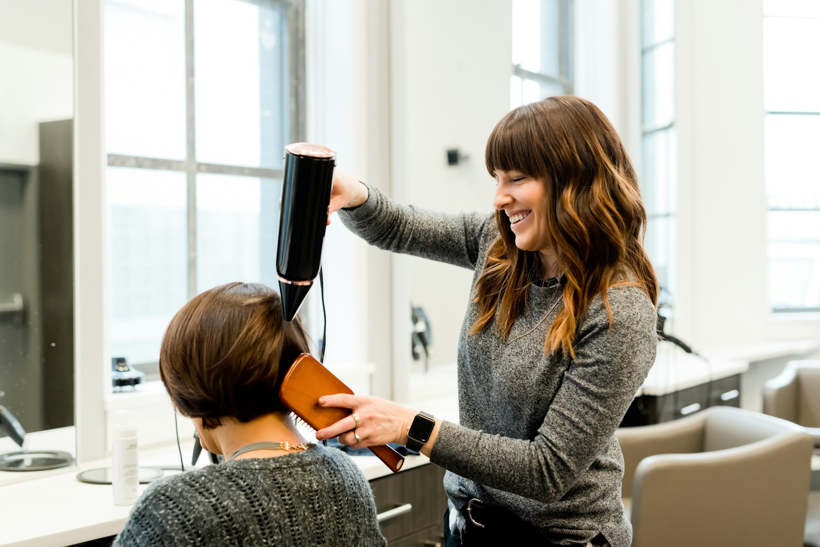Profesional secando el cabello de una clienta en un salon de peluqueria